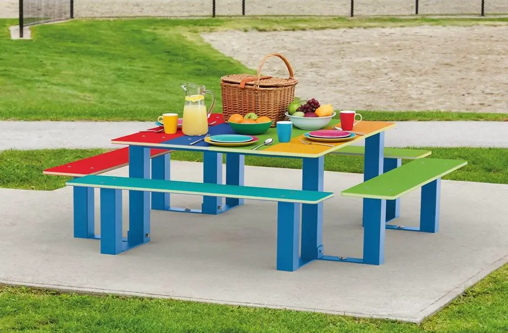 Table de pique-nique colorée en extérieur avec panier et boissons, surherbes et assiettes. outil de jardinage essentiels? intégré sans forcer.